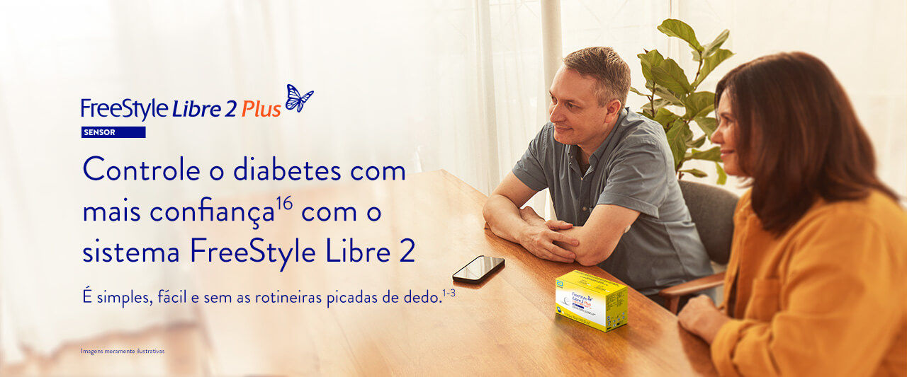 Homem e mulher apoiandos sobre a mesa com um smartphone e uma caixa do sensor FreeStyle Libre 2 Plus