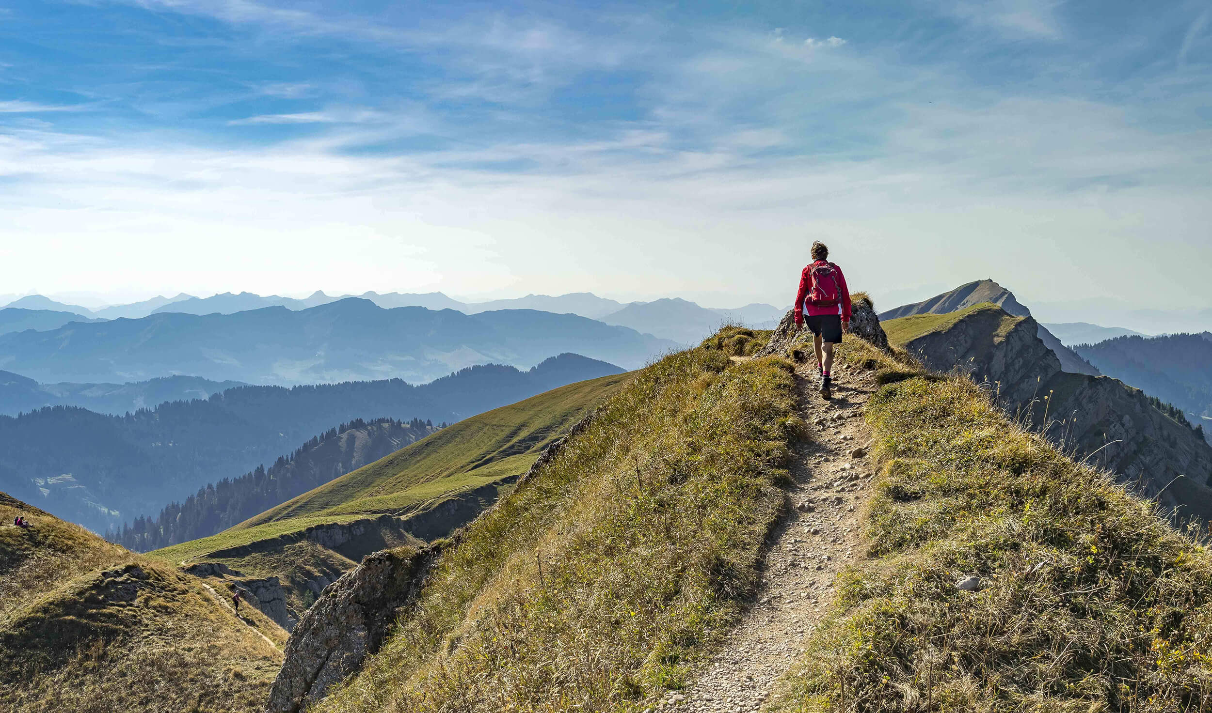 Mann wandert durch die Berge mit Blick auf Alpenpanorama
