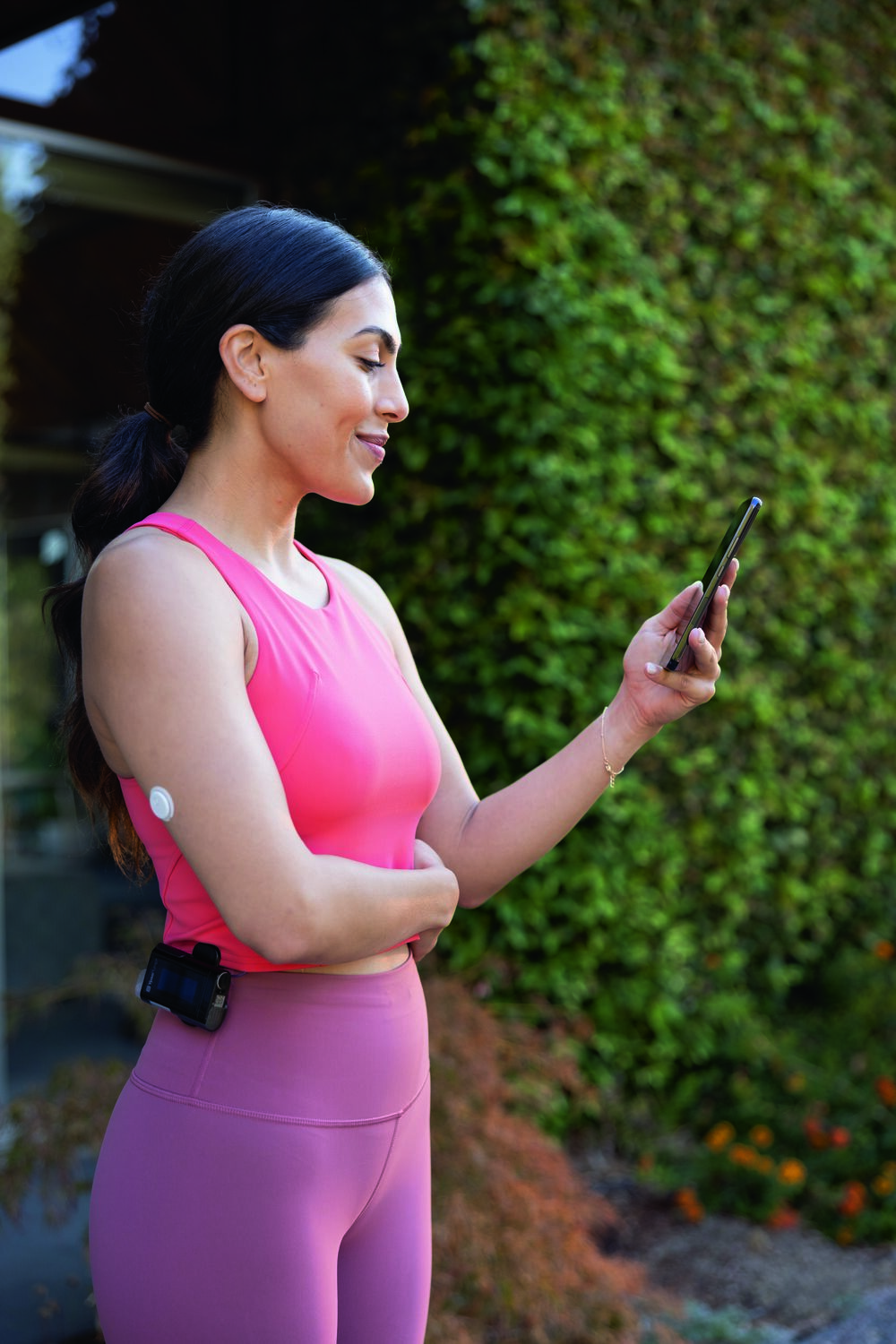 vrouw kijk op haar smartphone met FreeStyle Libre 3 op haar arm en mylife Loop