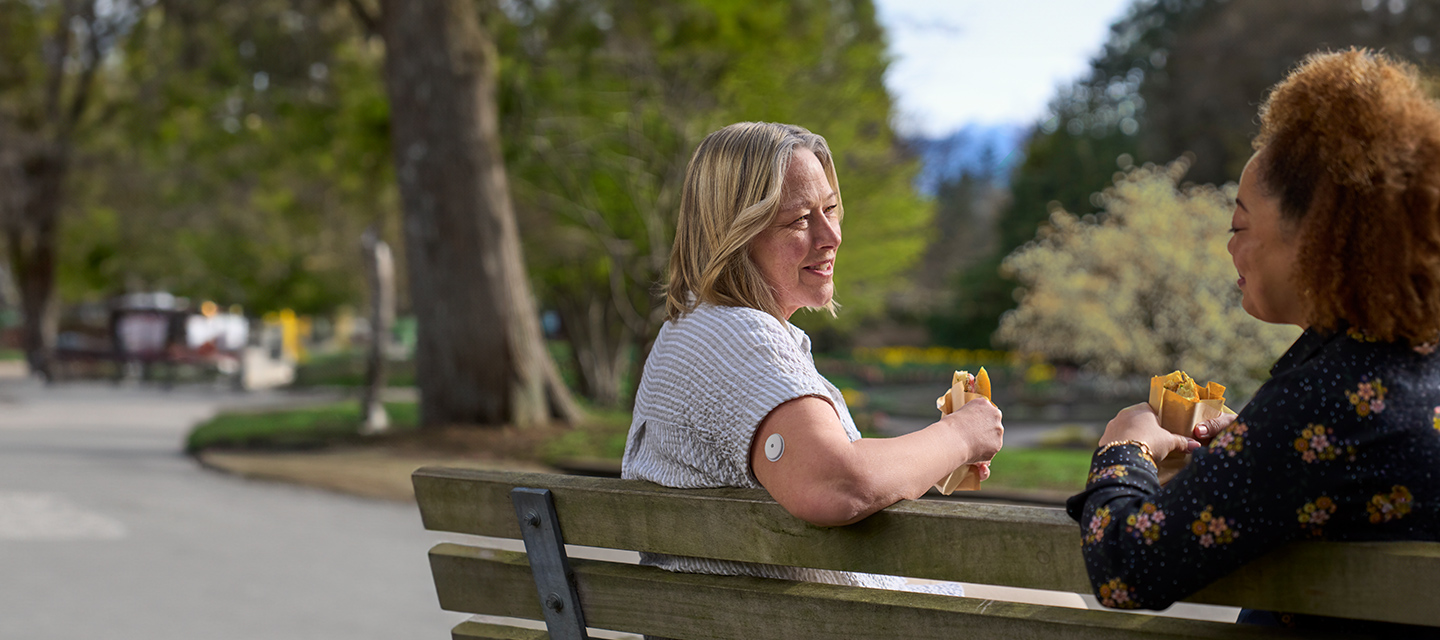 Woman wearing a FreeStyle Libre sensor eating sandwich with her friend