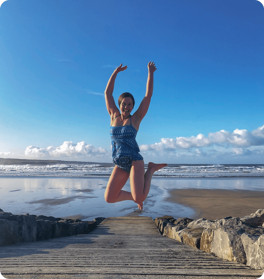 Erin, blog author, Jumping and laughing on the sand in front of the ocean