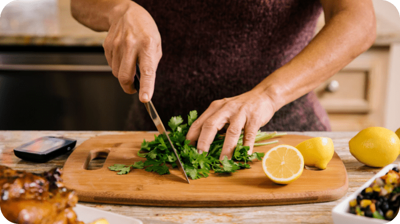 A man chopping coriander on a chopping board next to some lemons