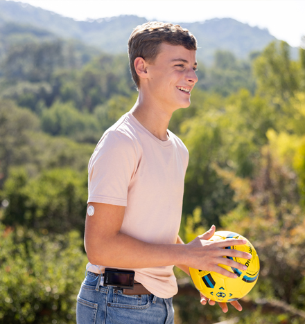 Boy with a FreeStyle Libre 3 sensor holding a ball 