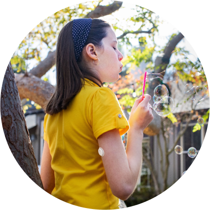 Girl blowing bubbles while wearing a FreeStyle Libre continuous glucose monitoring (CGM) sensor